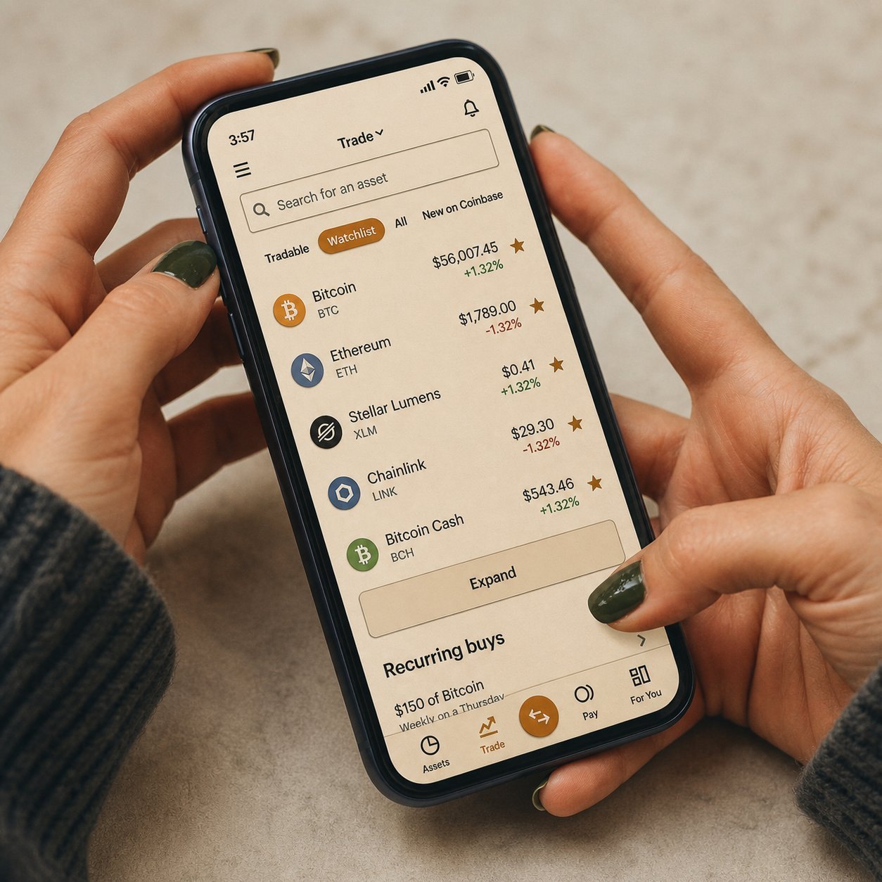 Hands holding a phone with the Coinbase trading app open, watchlist of cryptocurrencies visible